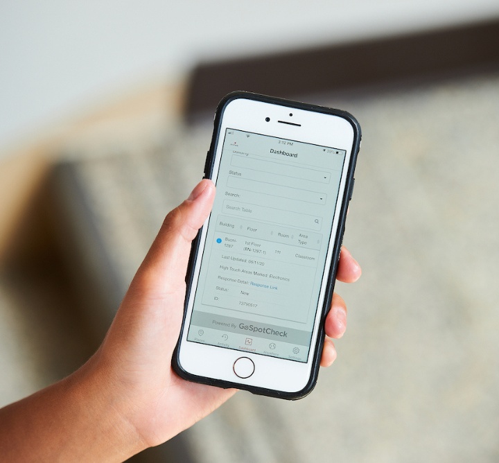 A hand holding a phone with a Facilities app open.